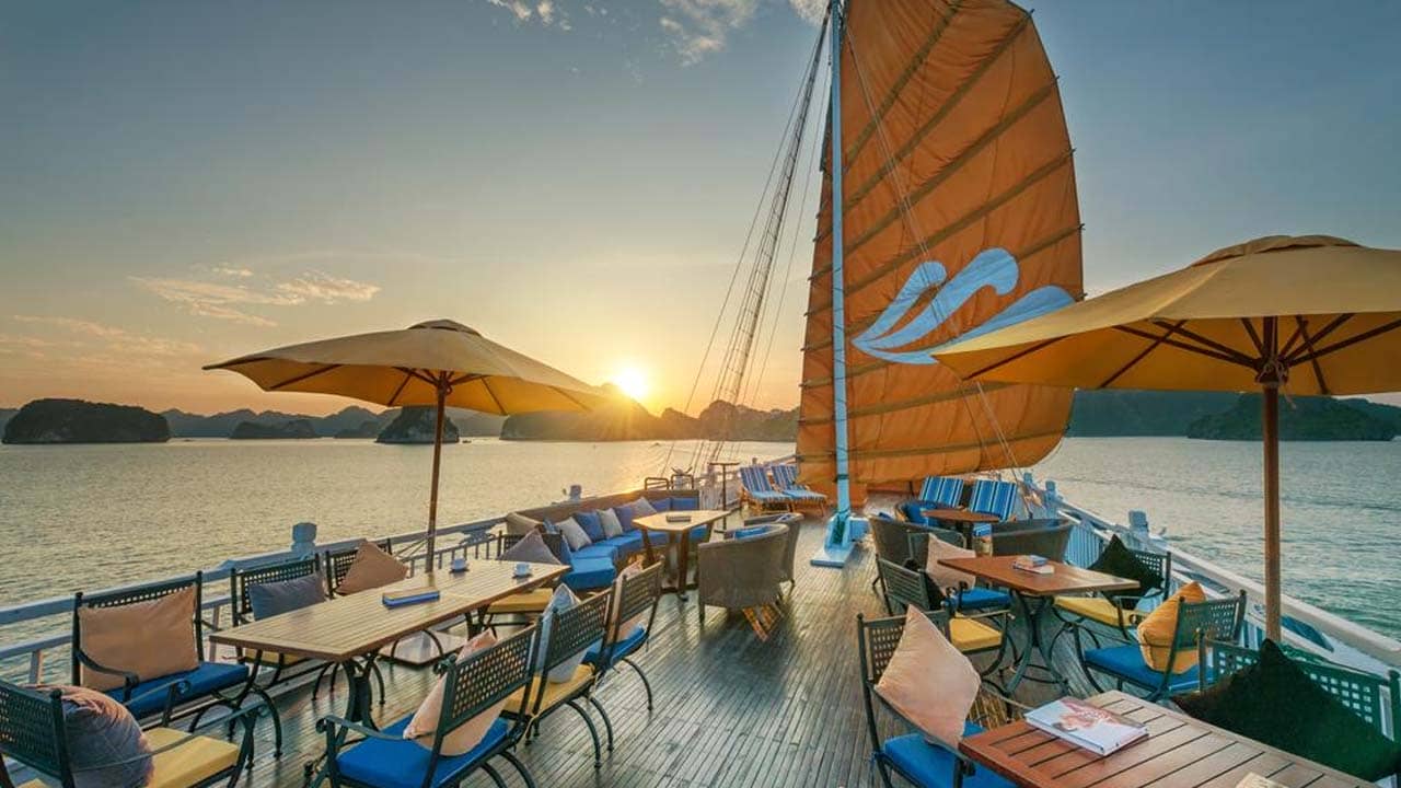 Nhâm nhi đồ uống và ngắm cảnh hoàng hôn trên vịnh Hạ Long từ boong tàu. Nguồn: Internet